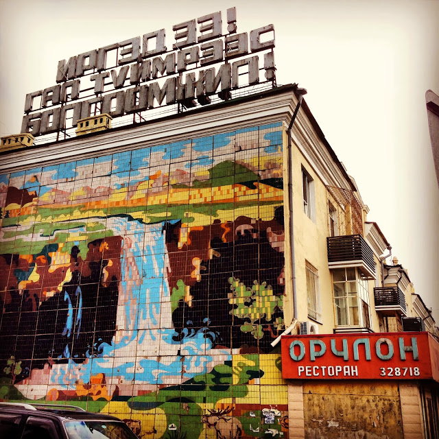 A mosaic depicting the Orkhon Waterfall in Ovorkhangai Aimag in Mongolia, decorating the end of a building in Ulaanbaatar. What language is spoken is a popular question about Mongolia.